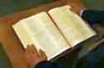 An image of hands on an open Bible.