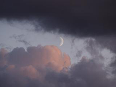 A photo of the Moon behind some clouds.