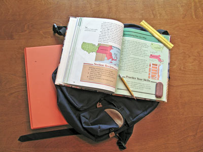 A photo of a backpack, notebook, and open textbook.