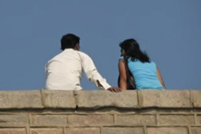 A photographic image of a man and woman sitting on a wall.