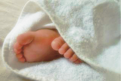 A photographic image of a baby's feet sticking outside a blanket.