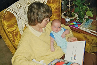 A photographic image of Mary reading a story to Baby Aiden.