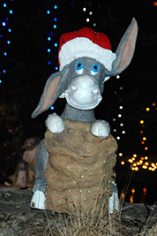 A photographic image of a statue of a donkey wearing a Santa hat.
