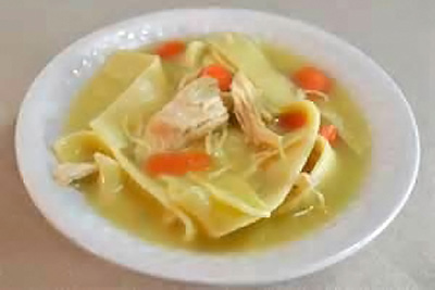 A photographic image of a bowl of chichen noodle soup.