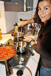 A photographic image of a woman coking a meal.