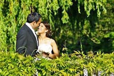 A photographic image of a bride and groom beneath a tree.