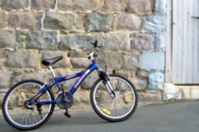 A photographic image of an unlocked bicycle by a door.