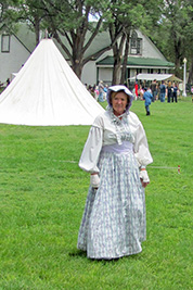 A photographic image of a volunteer in a 19th-century dress and hat.