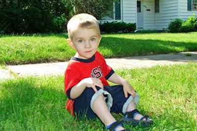 A photographic image of a little boy in a front yard.