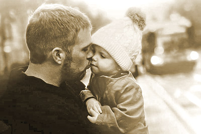A photographic image of a father kissing a baby girl.