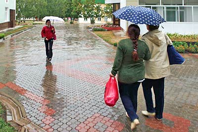 A photographic image of two women sharing an umbrella.