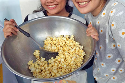 A photographic image of two girls making popcorn.