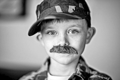 A photographic image of a boy with a mustache