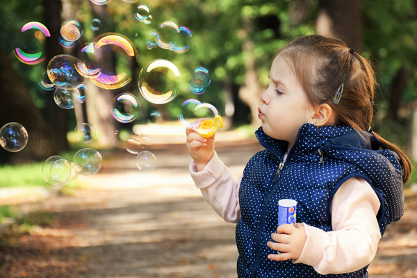 A photographic image of a girl blowing bubbles.