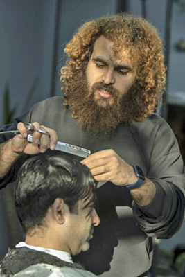 A photographic image of a man having his hair styled.